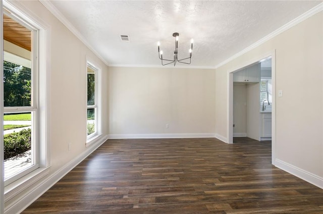 unfurnished dining area with dark wood-type flooring, a textured ceiling, crown molding, sink, and a chandelier