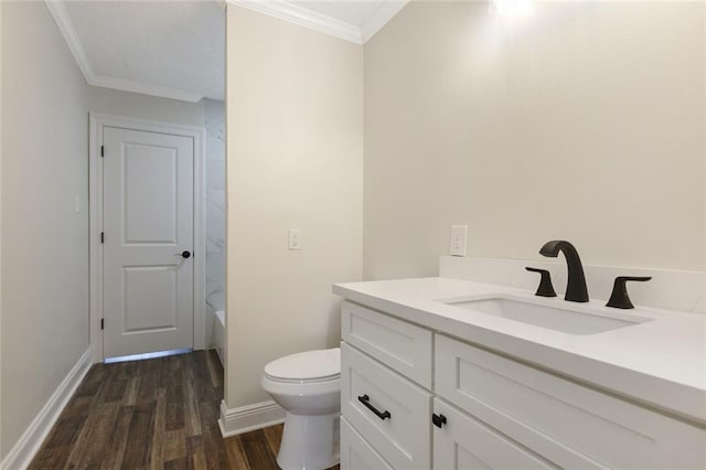 bathroom with wood-type flooring, toilet, crown molding, vanity, and a bathing tub