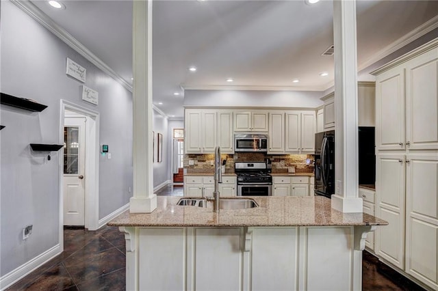 kitchen with a kitchen island with sink, sink, decorative columns, stainless steel appliances, and light stone countertops