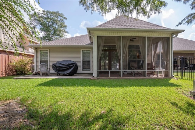 rear view of property featuring a sunroom, a patio area, and a lawn