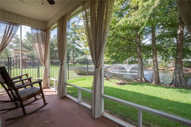 unfurnished sunroom with ceiling fan and a water view