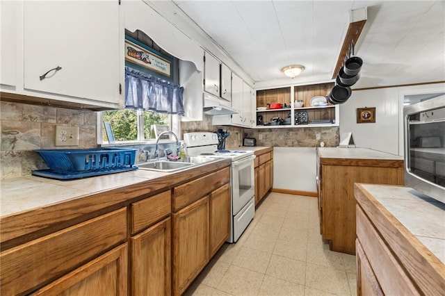 kitchen with white electric range oven, sink, backsplash, white cabinetry, and tile countertops