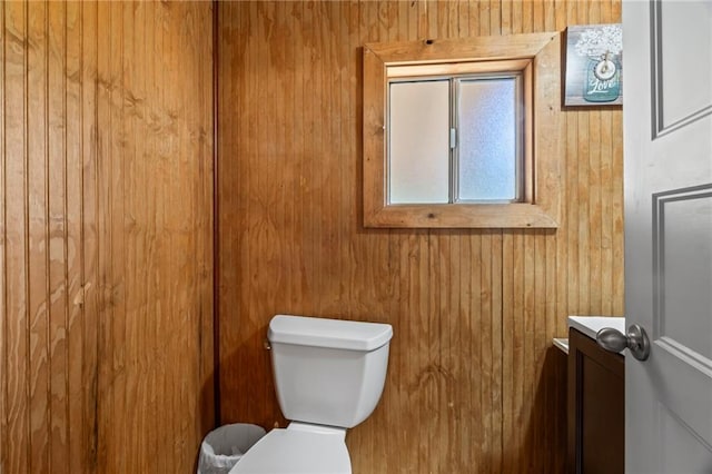 bathroom featuring wooden walls, vanity, and toilet