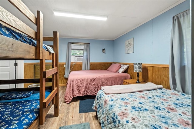 bedroom featuring light hardwood / wood-style flooring, wooden walls, cooling unit, and crown molding