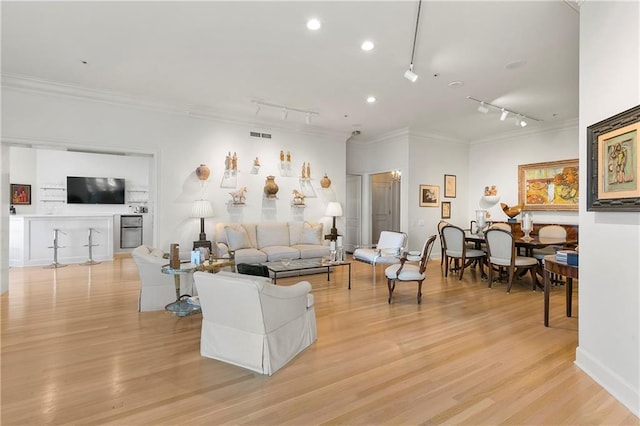 living room with crown molding, light hardwood / wood-style flooring, and track lighting