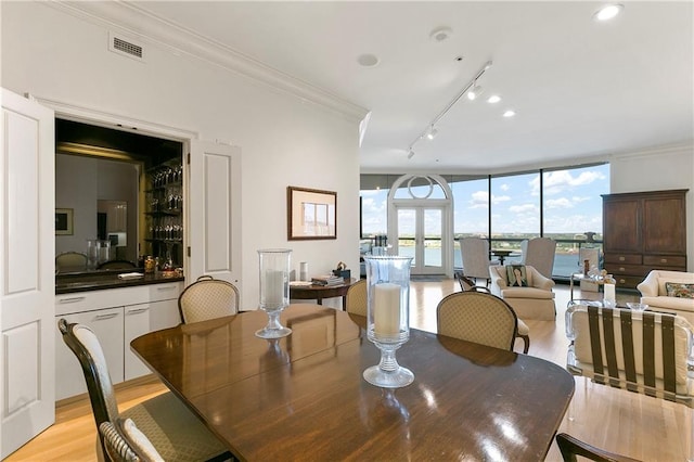 dining area featuring ornamental molding, light hardwood / wood-style floors, and a healthy amount of sunlight