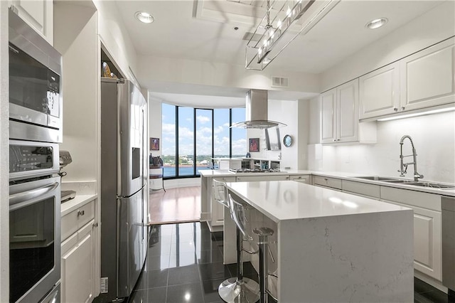 kitchen featuring sink, white cabinets, a kitchen island, stainless steel appliances, and extractor fan