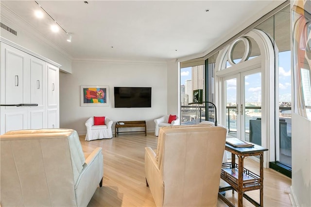 living room with light hardwood / wood-style floors, track lighting, floor to ceiling windows, crown molding, and french doors