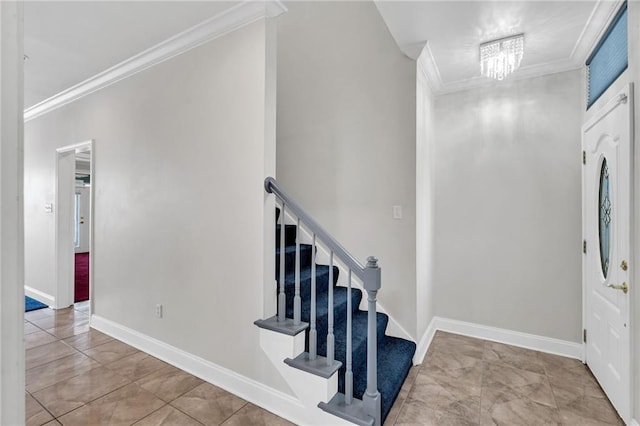 tiled foyer featuring ornamental molding and a chandelier