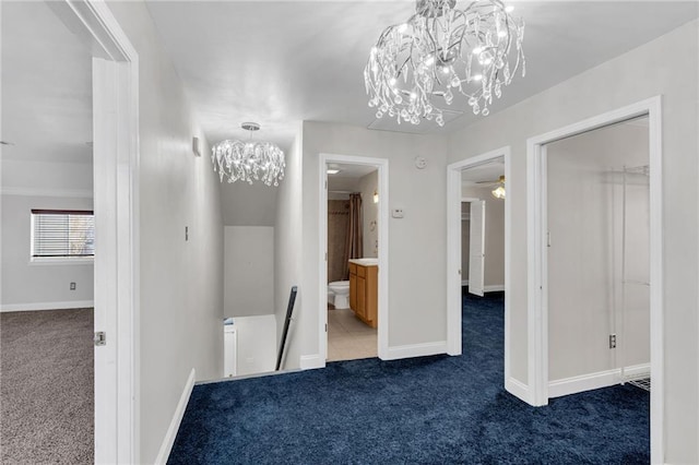 hall featuring a notable chandelier and dark colored carpet