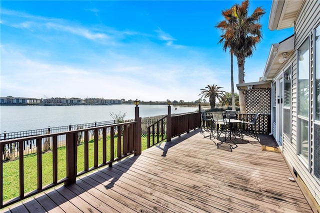 wooden terrace with a water view and a lawn