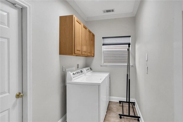 clothes washing area featuring light tile patterned floors, washer and clothes dryer, ornamental molding, and cabinets