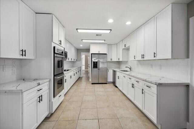 kitchen with appliances with stainless steel finishes, light tile patterned floors, and white cabinets