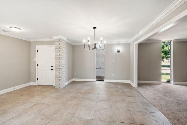 interior space with crown molding, a chandelier, and ornate columns