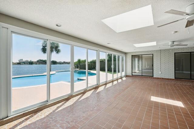 view of pool with a water view, ceiling fan, and a skylight