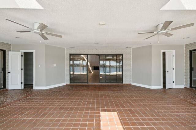 empty room featuring a textured ceiling, ceiling fan, and a skylight