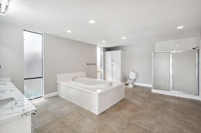 full bathroom with independent shower and bath, vanity, toilet, and tile patterned floors