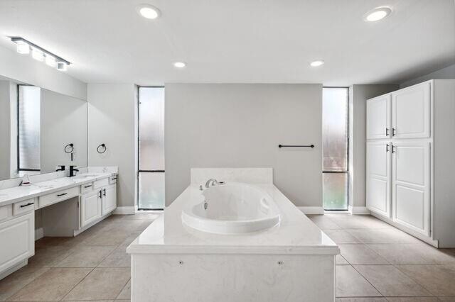 bathroom with vanity, a wealth of natural light, tile patterned floors, and a tub