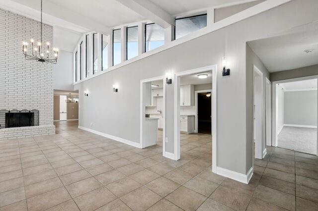 unfurnished living room featuring a fireplace, light tile patterned flooring, beamed ceiling, and high vaulted ceiling