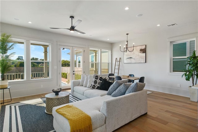 living room featuring french doors, ceiling fan with notable chandelier, hardwood / wood-style floors, and a healthy amount of sunlight