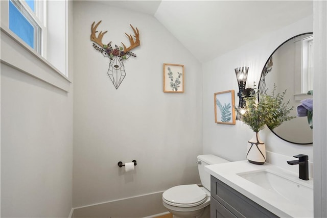 bathroom with lofted ceiling, vanity, and toilet