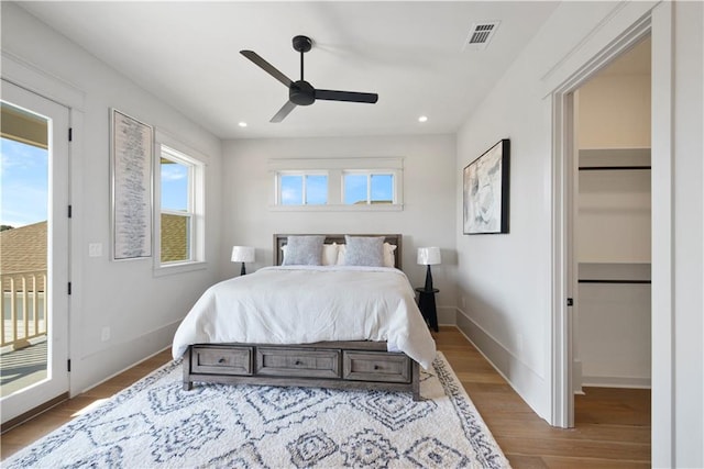 bedroom with ceiling fan, multiple windows, hardwood / wood-style flooring, and access to outside