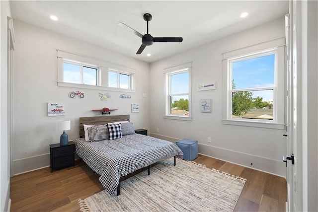 bedroom featuring ceiling fan, hardwood / wood-style flooring, and multiple windows