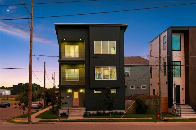 contemporary home featuring a balcony, fence, and entry steps