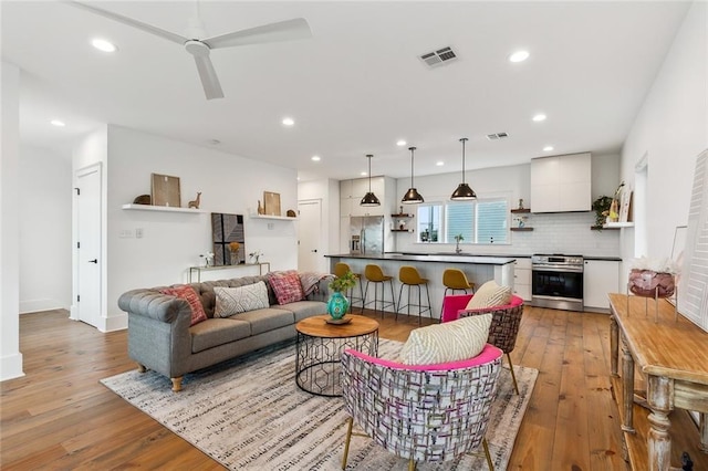 living room with light wood finished floors, recessed lighting, visible vents, and a ceiling fan