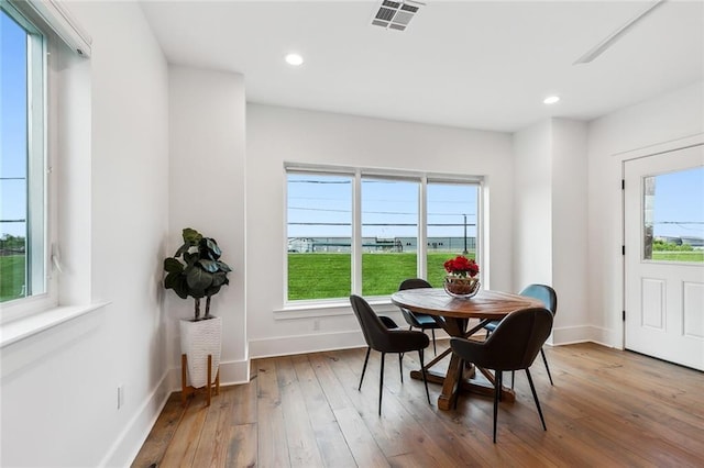 dining room with a wealth of natural light, wood-type flooring, visible vents, and baseboards