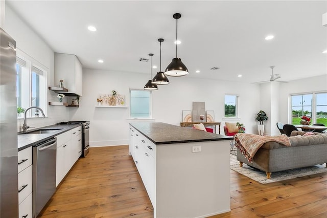 kitchen with a kitchen island, appliances with stainless steel finishes, light wood-type flooring, open shelves, and a sink