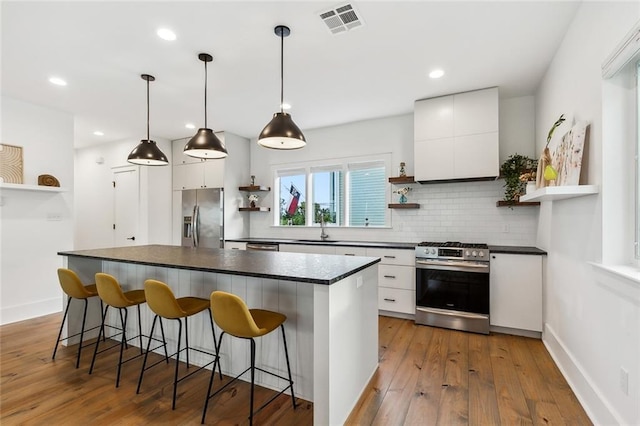 kitchen featuring hanging light fixtures, stainless steel appliances, light wood-type flooring, and white cabinetry