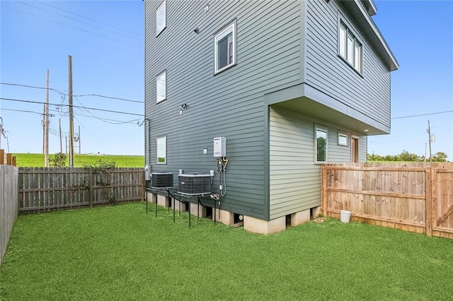 rear view of property featuring a fenced backyard, a yard, and central AC unit