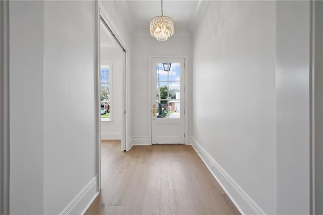 doorway to outside with light hardwood / wood-style floors, a notable chandelier, and ornamental molding