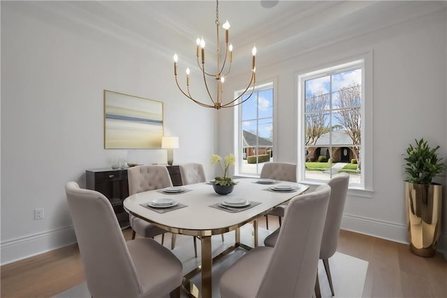 dining space with baseboards, wood finished floors, a notable chandelier, and crown molding