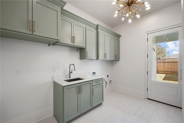 washroom with hookup for an electric dryer, sink, gas dryer hookup, a notable chandelier, and cabinets