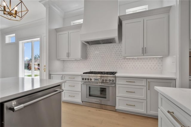 kitchen with premium range hood, stainless steel appliances, light hardwood / wood-style floors, crown molding, and decorative light fixtures