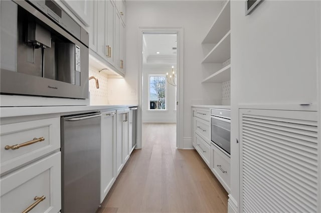 kitchen with light hardwood / wood-style floors, white cabinets, stainless steel appliances, and backsplash