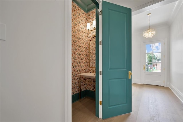 doorway to outside featuring light hardwood / wood-style flooring, a notable chandelier, and crown molding