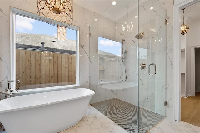 full bath featuring a chandelier, a soaking tub, marble finish floor, and a marble finish shower
