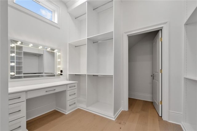 walk in closet featuring built in desk and light wood-type flooring