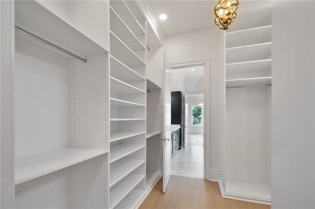 walk in closet with light hardwood / wood-style flooring