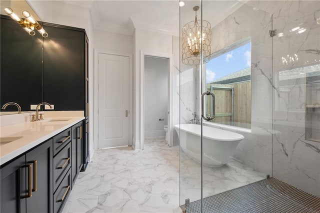 full bath with double vanity, a freestanding bath, an inviting chandelier, marble finish floor, and crown molding