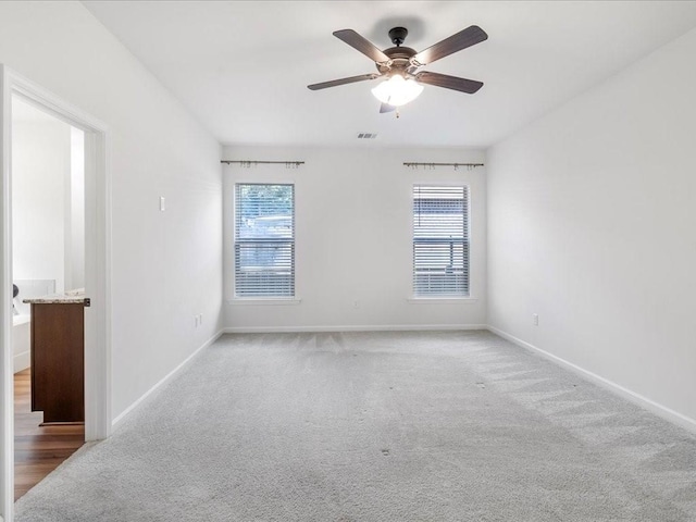 spare room featuring carpet floors, ceiling fan, and a wealth of natural light