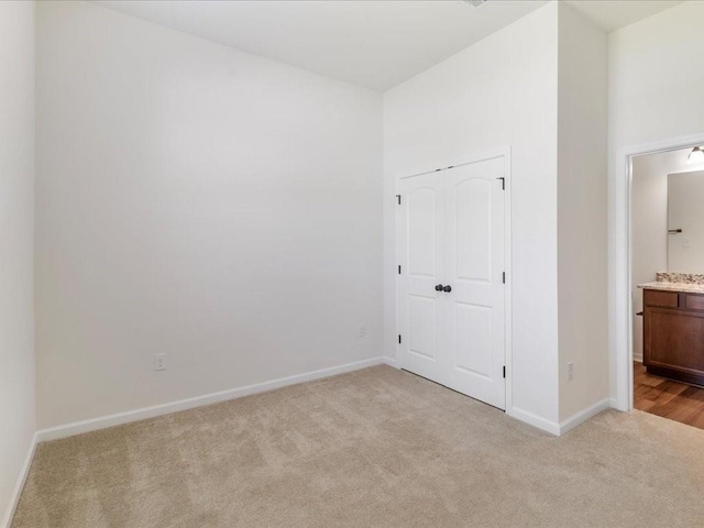 unfurnished bedroom with light colored carpet and ensuite bath