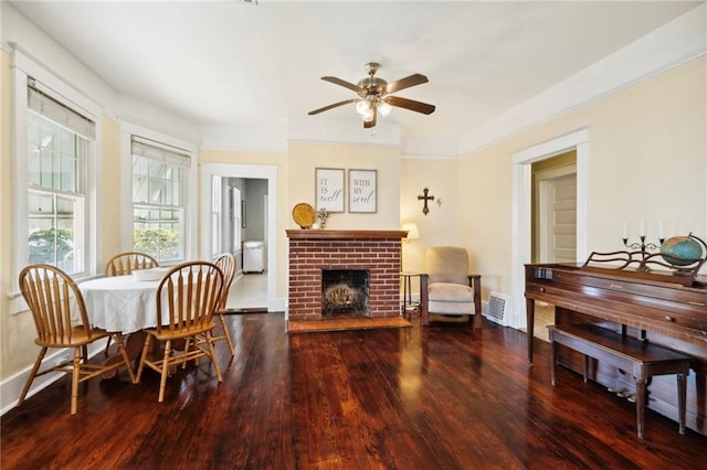 dining space featuring a brick fireplace, wood-type flooring, and ceiling fan