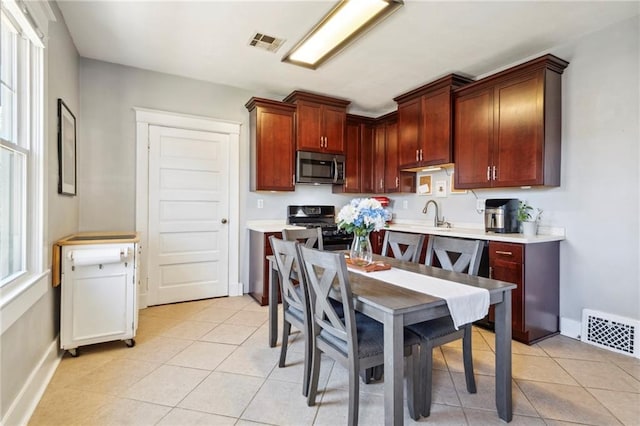 kitchen featuring light tile patterned flooring, black stove, and sink