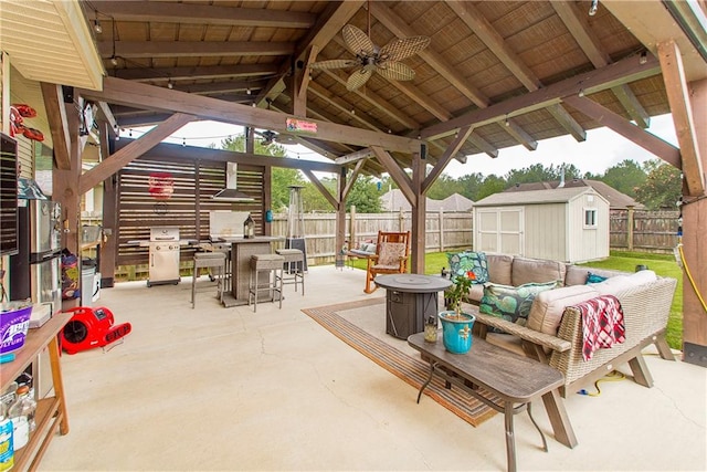 view of patio / terrace featuring ceiling fan, an outdoor living space with a fire pit, and a shed