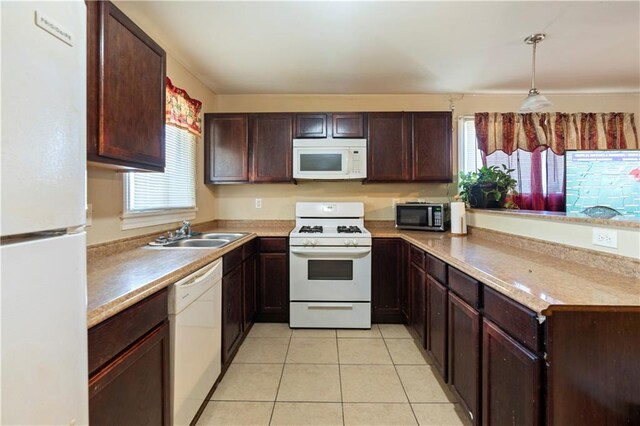 kitchen with light tile patterned floors, sink, white appliances, dark brown cabinets, and decorative light fixtures