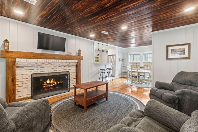 living room with a fireplace, hardwood / wood-style floors, wooden ceiling, and wood walls